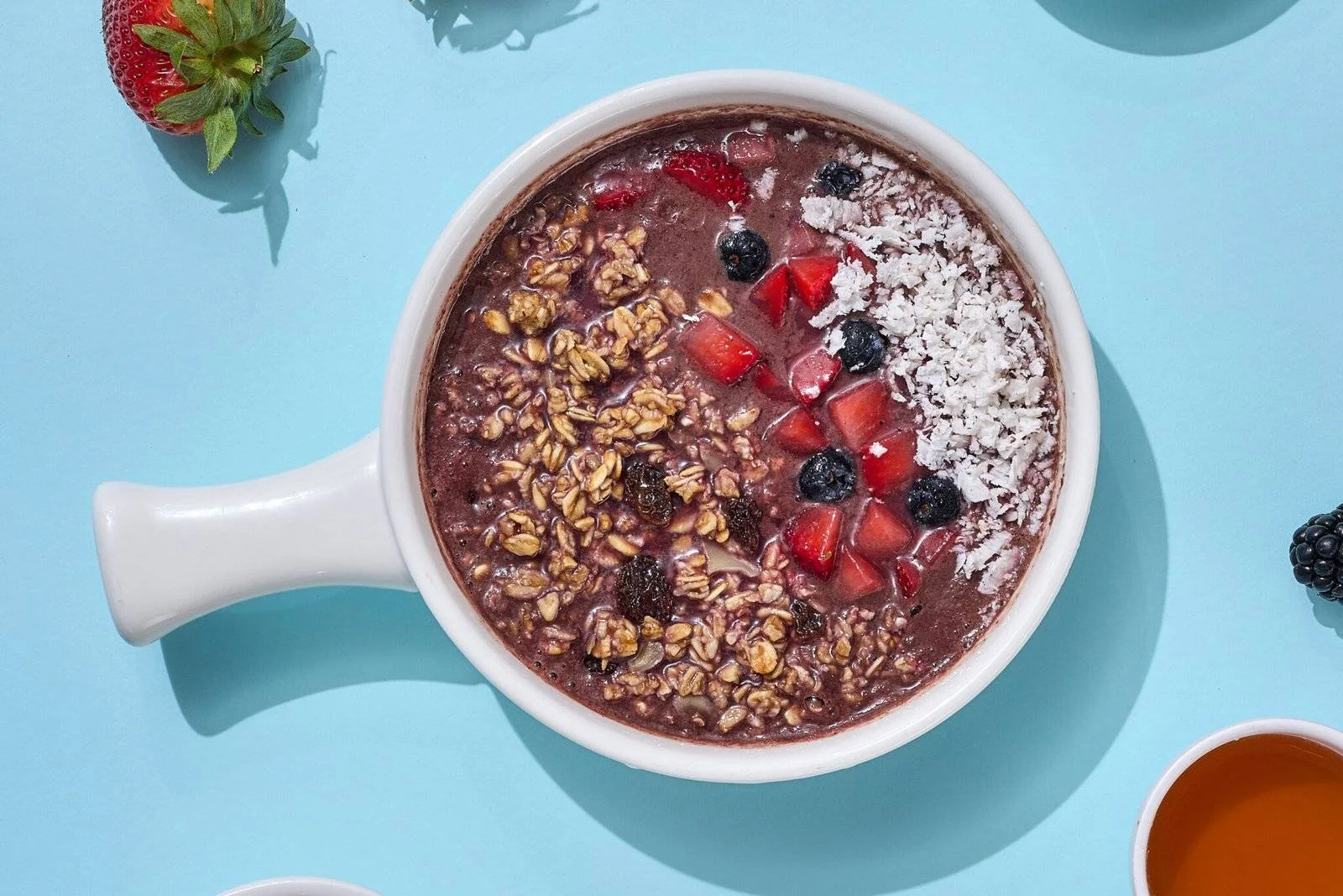 A healthy acai bowl topped with granola, fresh berries, and coconut, a perfect meal for a busy peoples