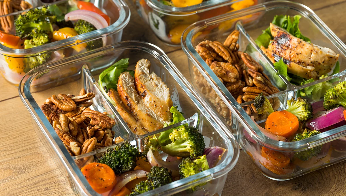 Image of a grilled chicken, vegetables, and nuts in meal prep containers, ready to eat keto meals.